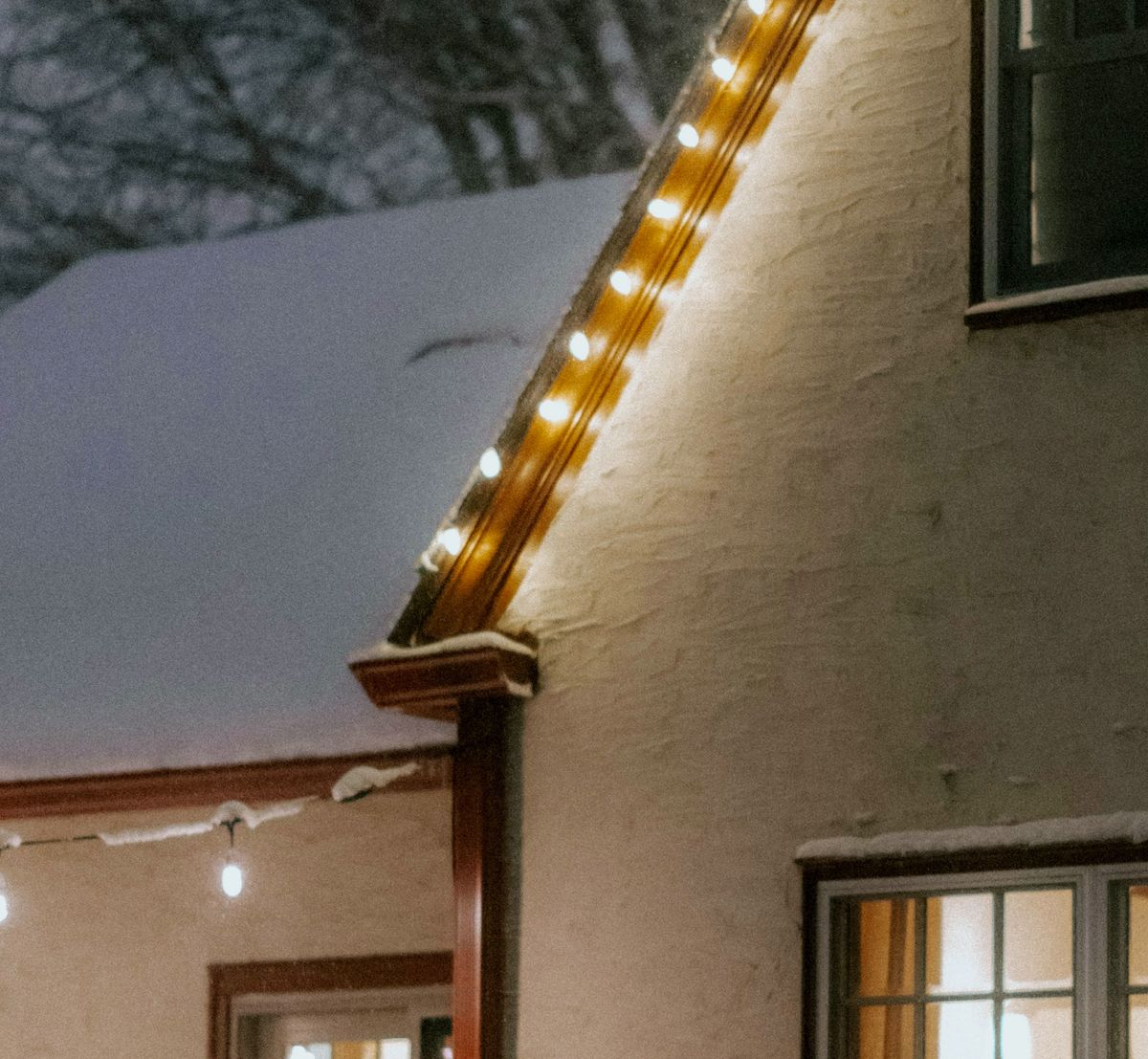 Close view of warm white C9 bulbs clipped in a straight line along a snowy roof edge