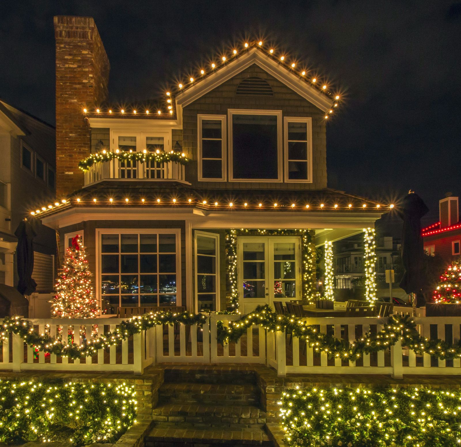 Two-story shingle home with warm white C9 bulbs tracing every roofline at night